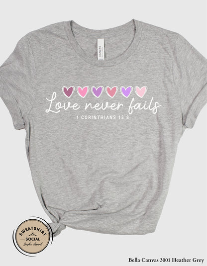 Love Never Fails White Valentine Shirt – 1 Corinthians 13:8 Heart Design (Adult Sizes S–2XL)