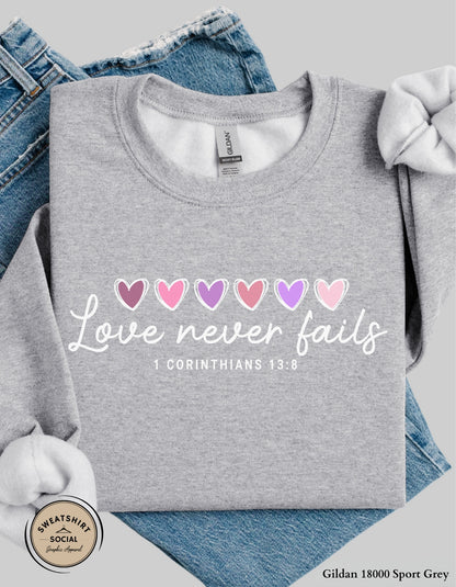 Love Never Fails White Valentine Shirt – 1 Corinthians 13:8 Heart Design (Adult Sizes S–2XL)