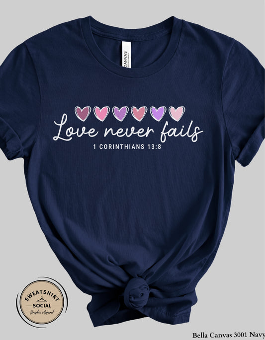 Love Never Fails White Valentine Shirt – 1 Corinthians 13:8 Heart Design (Adult Sizes S–2XL)