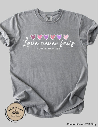 Love Never Fails White Valentine Shirt – 1 Corinthians 13:8 Heart Design (Adult Sizes S–2XL)